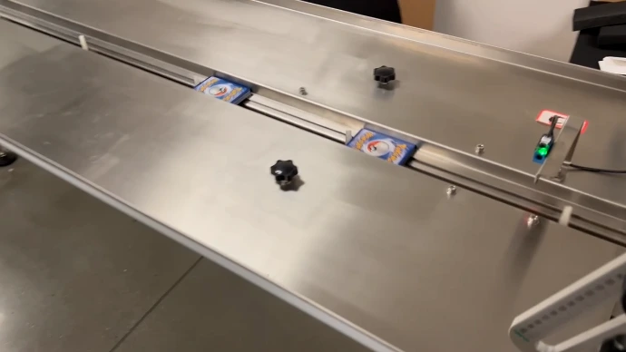 Flow wrapper conveyor with adjustable card guides