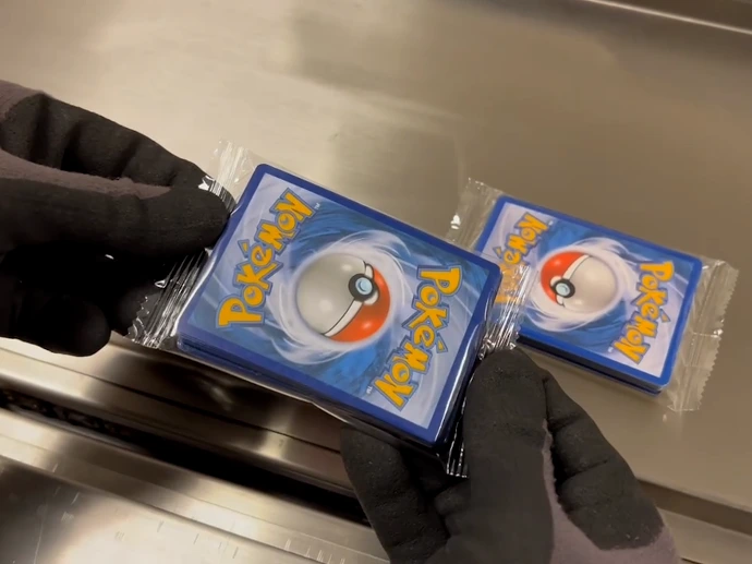 Wrapped trading card packs exiting automated wrapper