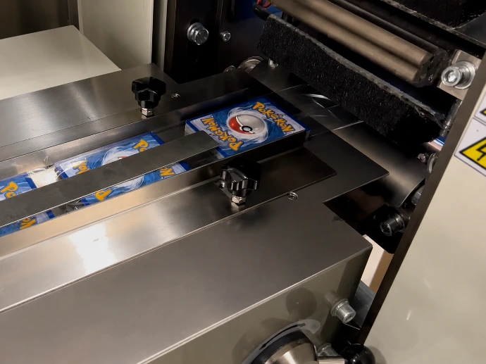 Trading card pack entering flow wrapper sealing area